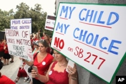 FILE - Protesters decry a measure requiring California schoolchildren to get vaccinated, at a Capitol rally, June 9, 2015, in Sacramento, Calif. The bill, SB277, which allowed only children with serious health problems to opt out of school-mandated vaccinations, became law and took effect in 2016.