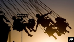 FILE - In this July 23, 2009 photo, children are silhouetted by the setting sun as they ride a swing ride during the Canyon County Fair in Caldwell, Idaho. New results published in JAMA Pediatrics suggests being overweight or obese might affect brain development in children.