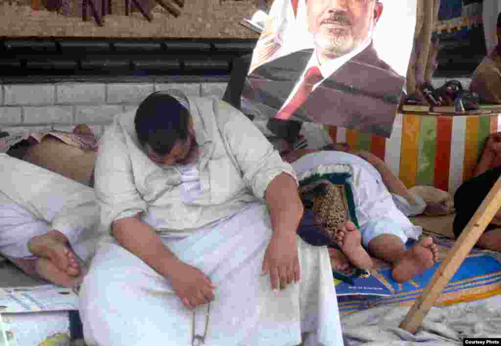 Exhaused Morsi supporter resting outside Muslim Brotherhood stronghold outside Cairo&#39;s Rabaa al-Adawiya mosque, July 11. Photo: VOA/Sharon Behn
