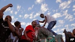 Des étudiants placent un seau sur la tête de la statue de Cecil John Rhodes, lors du retrait définitif de la statue du campus de l'université du Cap, en Afrique du Sud, le 9 avril 2015. (AP Photo/Schalk van Zuydam)