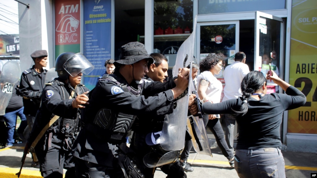 Policías antidisturbios desalojan a periodistas desde la entrada principal de su medio hasta una estación de policía en Managua, Nicaragua, el 15 de diciembre del 2018.