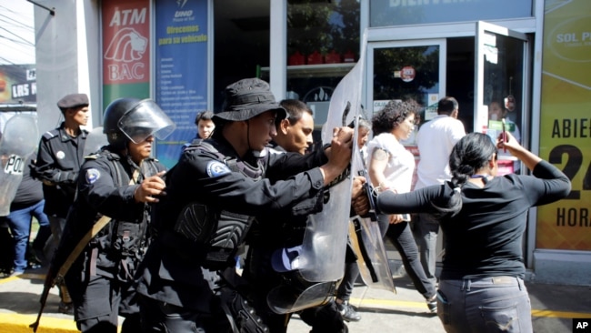 Policías antidisturbios desalojan a periodistas desde la entrada principal de su medio hasta una estación de policía en Mangua, Nicaragua, el 15 de diciembre del 2018
