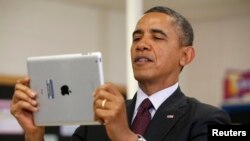FILE - President Barack Obama holds up an Apple iPad during a visit to Buck Lodge Middle School in Adelphi, Maryland, Feb. 4, 2014.
