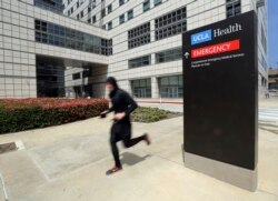 Seorang pria berlari melintas di depan gedung Ronald Reagan UCLA Medical Center di kampus Universitas California, Los Angeles, 26 April 2019. (Foto: AP)