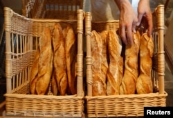 A baker places freshly-baked baguettes, the traditional French bread, in baskets in his shop in Strasbourg, eastern France, Aug. 2010.