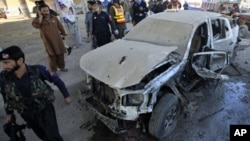 A policeman walks past a vehicle damaged by a suicide bomb attack on the outskirts of Peshawar January 31, 2011.