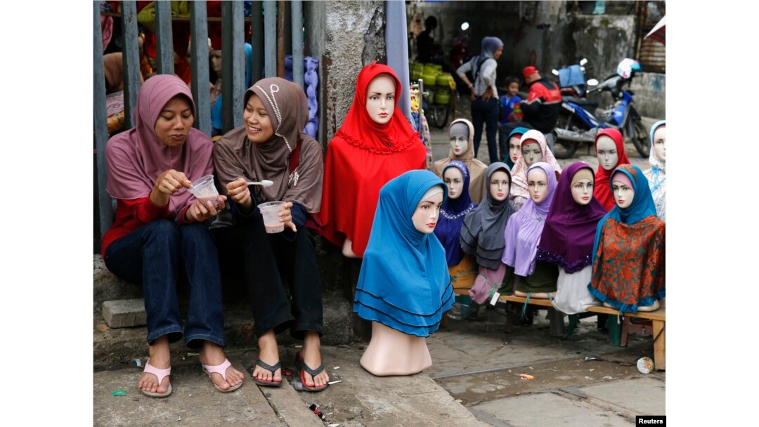 Dua perempuan duduk dekat boneka peraga yang mengenakan hijab-hijab untuk dijual di Pasar Tanah Abang menjelang bulan Ramadan, Jakarta, 27 Juni 2014.