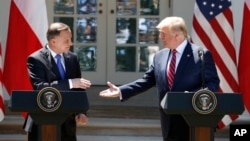 President Donald Trump and Polish President Andrzej Duda reach to shake hands at a news conference in the Rose Garden of the White House, in Washington, June 12, 2019. 