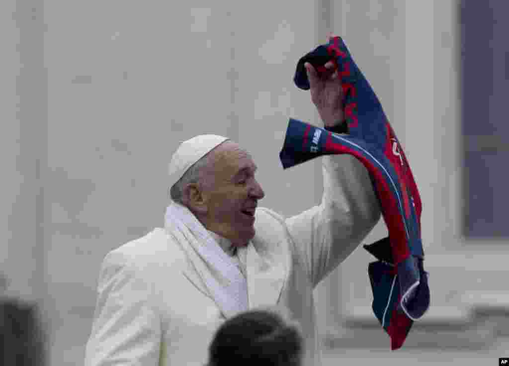 Đức Giáo hoàng Phan-xi-cô chụp lấy một chiếc áo ném về phía ông trong buổi giáo dân tiếp kiến hàng tuần tại quảng trường Thánh Phêrô ở Vatican.
