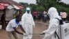 FILE - Health workers wash their hands after taking a blood specimen from a child to test for the Ebola virus in a area were a 17-year old boy died from the virus on the outskirts of Monrovia, Liberia, June 30, 2015.