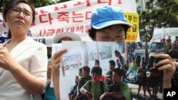 Người biểu tình tại Seoul cầm hình ảnh 9 thanh niên Bắc Triều Tiên bị trả về nước.
