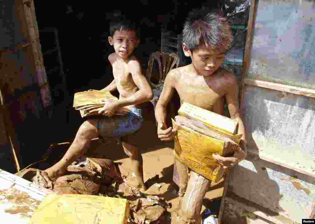 Boys recover school materials in a house inundated by mud brought by Typhoon Hagupit in Borongan city, Samar, Philippines, Dec. 8, 2014.