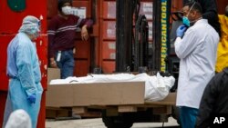 Un cuerpo envuelto en plástico va a ser colocado en u camión refrigerado usado como morgue temporaria en la ciudad de Nueva York debido a la pandemia de COVID-19 el 31 de marzo de 2020.