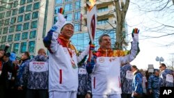 Chủ tịch Ủy ban Olympic Quốc tế Thomas Bach (phải) chuyền ngọn đuốc cho Tổng thư ký LHQ Ban Ki-moon bên dòng sông Sochi, 6/2/14