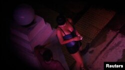 FILE - A sex worker talks to a man outside a hotel in the Geylang red light district in Singapore. Khu said the head of the organization, who was based in Thailand, was recently arrested in Belgium for separate trafficking offenses there. 