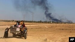 In this April 4, 2016 file photo, smoke rises as people flee their homes during clashes between Iraqi security forces and members of the Islamic State group in Hit, Iraq.