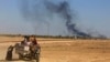 In this April 4, 2016 file photo, smoke rises as people flee their homes during clashes between Iraqi security forces and members of the Islamic State group in Hit, Iraq.