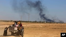 In this April 4, 2016 file photo, smoke rises as people flee their homes during clashes between Iraqi security forces and members of the Islamic State group in Hit, Iraq.