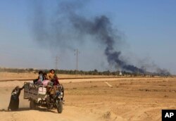 In this April 4, 2016 file photo, smoke rises as people flee their homes during clashes between Iraqi security forces and members of the Islamic State group in Hit, Iraq.