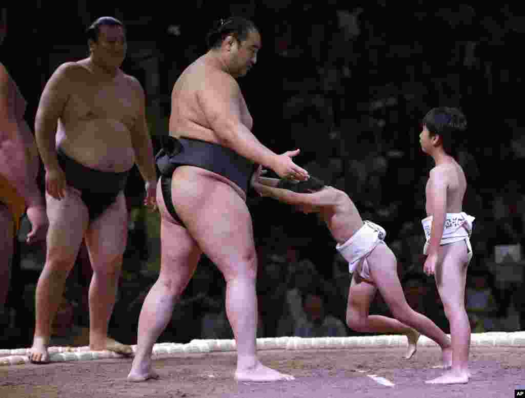 A boy tries to push a sumo wrestler during an exhibition titled "Sumo Tournament In Jakarta," at Istora stadium in Jakarta, Indonesia.