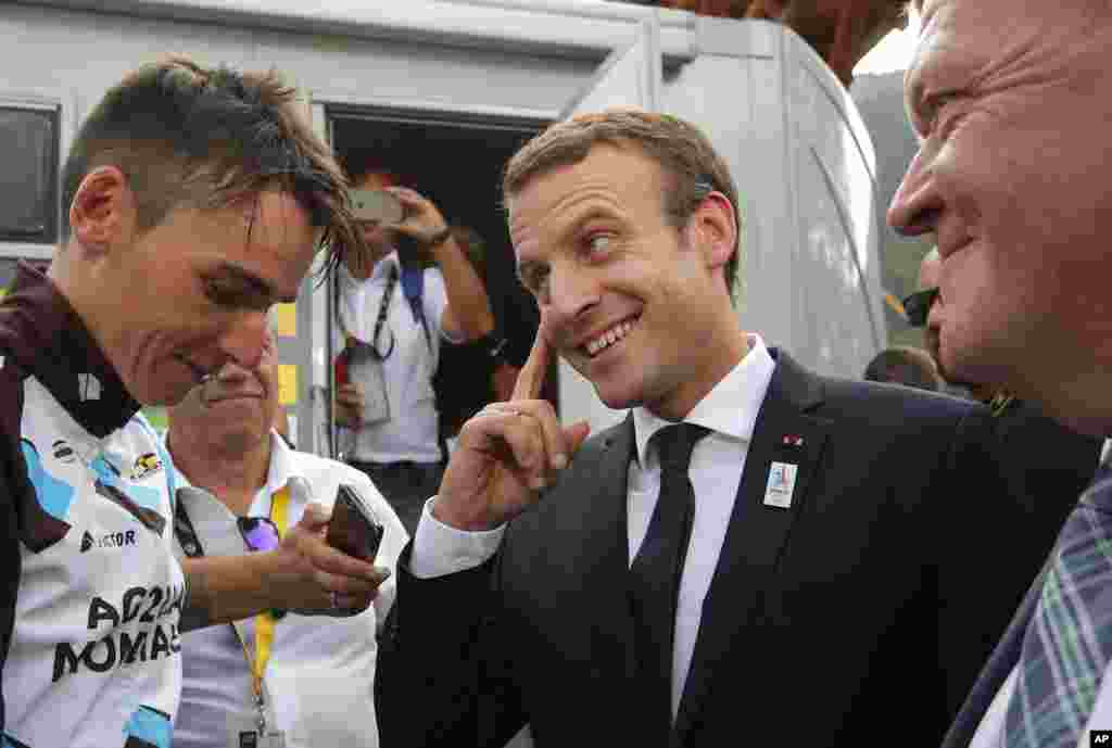 French President Emmanuel Macron talks to France's Romain Bardet as Danish Prime Minister Lars Lokke Rasmussen after the seventeenth stage of the Tour de France cycling race.
