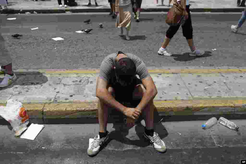 A protester sits on the road in front of the Greek Parliament during a protest in Athens, July 16, 2013.