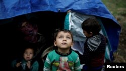 FILE PHOTO: A Syrian refugee boy stands in front of his family tent at a makeshift camp for refugees and migrants next to the Moria camp on the island of Lesbos, Greece, Nov. 30, 2017.