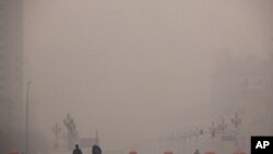 2012年1月18日两名行人走过被雾霾笼罩的北京街头
