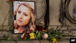 A portrait of slain television reporter Viktoria Marinova is placed on the Liberty Monument next to flowers and candles during a vigil in Ruse, Bulgaria, Oct. 9, 2018. 