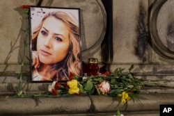 FILE - A portrait of slain television reporter Viktoria Marinova is placed on the Liberty Monument next to flowers and candles during a vigil in Ruse, Bulgaria, Oct. 9, 2018.
