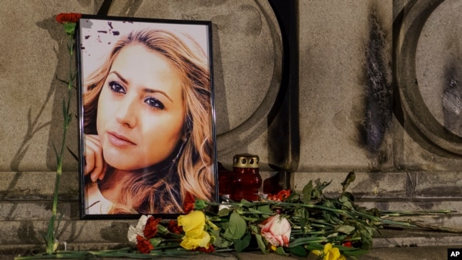 2018年10月9日，在保加利亚鲁塞的自由纪念碑举行的守夜活动期间，被杀害的电视记者维多利亚·马琳诺娃的肖像被放置在鲜花和蜡烛的旁边。