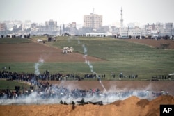 FILE - Israeli soldiers shoot tear gas toward Palestinian protesters as they gather on the Israel Gaza border, March 30, 2018.