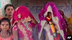 An underaged bride, right, stands with family members during her marriage at a Hindu temple near Rajgarh, Madhya Pradesh state, India, April 17, 2017.