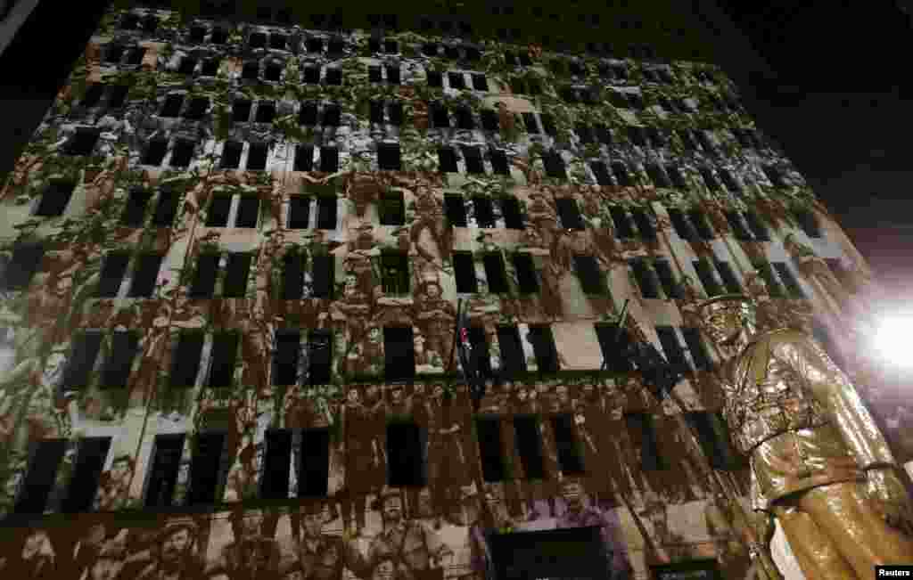 Old photographs of Australian soldiers are projected onto an office building alongside a bronze statue at the Cenotaph war memorial on ANZAC (Australian and New Zealand Army Corps) day in Sydney, April 25, 2015.