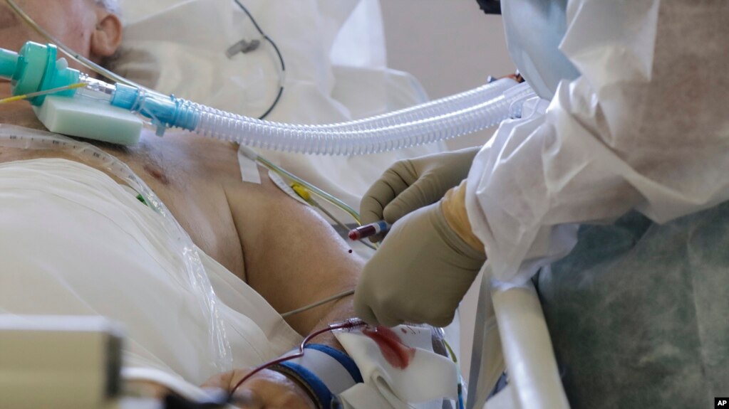 Doctor Davide Maraggia tends to a patient, in the Intensive Care Unit of the 'Ospedale di Circolo' hospital, in Varese, Italy, Friday, Nov. 6, 2020. Italy’s daily new COVID-19 caseload surged higher on Friday but so did the number of swab tests in the las