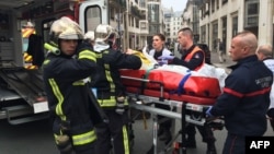 Bombeiros transportam um ferido após o ataque ao escritório do jornal Charlie Hebdo, em Paris. 7 Janeiro 2015