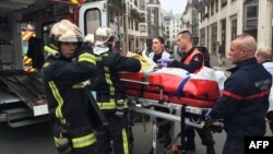 FILE - Firefighters carry an injured man on a stretcher in front of the offices of the French satirical newspaper Charlie Hebdo in Paris, Jan. 7, 2015, after armed gunmen stormed the offices, killing 12.