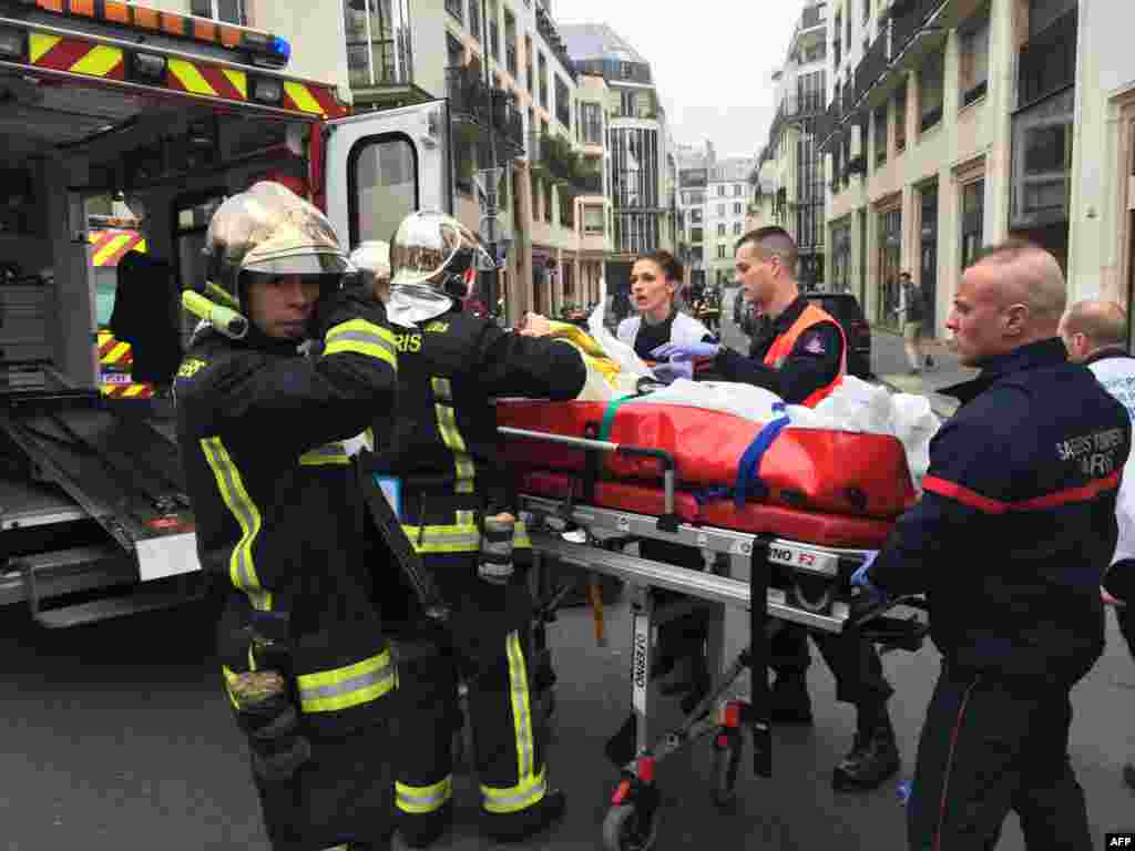 Wazima moto wakimbeba muathiriwa mmoja katika eneo la shambulio nje ya ofisi ya jarida Charlie Hebdo, Paris, Jan. 7, 2015.