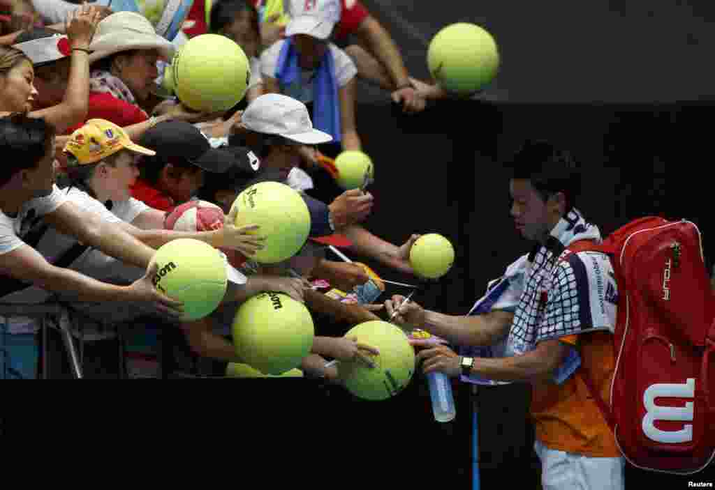 Kei Nishikori dari Jepang menandatangi bola tenis raksasa setelah memenangkan pertandingan babak pertamanya melawan petenis Jerman Philipp Kohlschreiber di turnamen tenis Australia Terbuka di Melbourne Park, Australia.