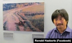 Nhân chứng vụ thảm sát Mỹ Lai Trần Văn Đức bên bức ảnh mà ông là bé trai trong đó do Ronald Haeberle chụp và được trung bày ở bảo tàng Sơn Mỹ với chú thích mà cựu phóng viên ảnh Mỹ yêu cầu được thay đổi cho đúng "sự thật lịch sử." (Facebook Ronald Haeberl
