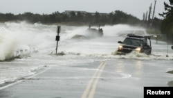 A truck drives through water pushed over a road by Hurricane Sandy in Southampton, New York, October 29, 2012.