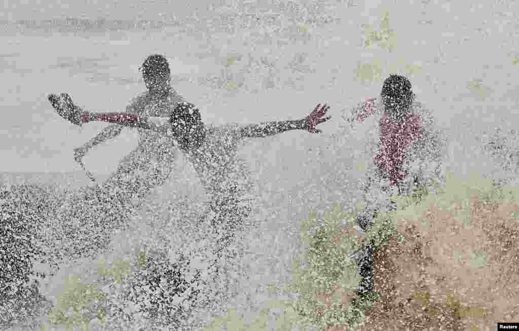 Men get wet from a large wave at the sea front in Mumbai, India.