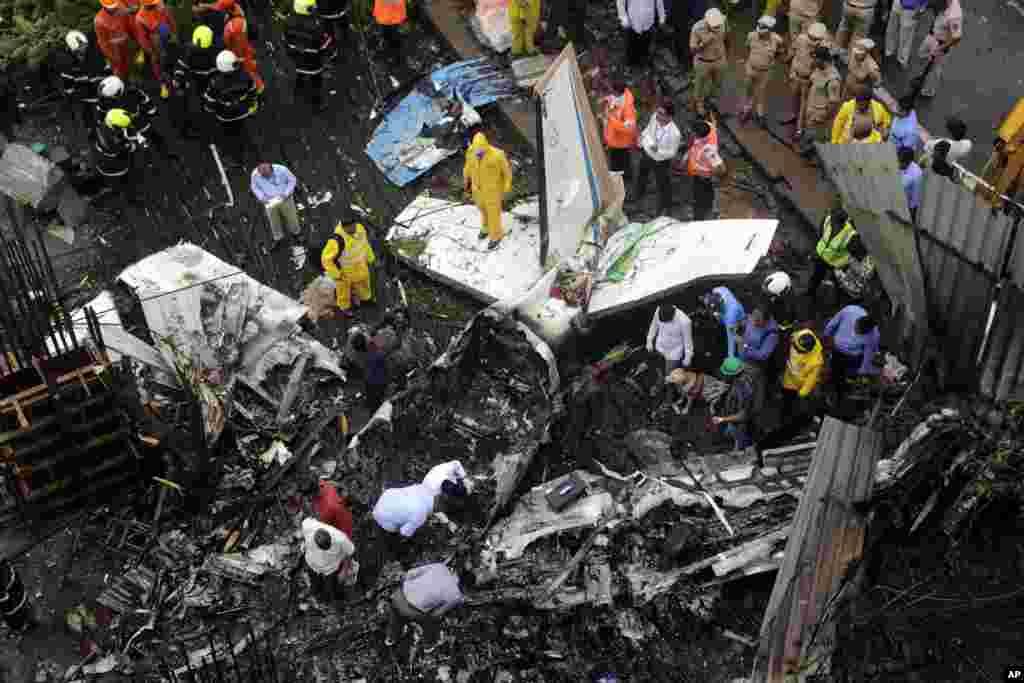 Rescuers stand amid the wreckage of a private chartered plane that crashed in Ghatkopar area, Mumbai, India.