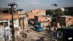 A military police helicopter flies over the Mandela shantytown, part of the Manguinhos slum complex, as policemen patrol the area on the ground after attacks to their Pacifying Police Unit post in Rio de Janeiro, March 21, 2014.