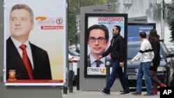 Young people pass beside boards with election posters of Gjorge Ivanov, (l), current Macedonian President and a candidate of the ruling conservative VMRO-DPMNE party, with a slogan "The State Before All", and Stevo Pendarovski, (c), a candidate of opposition Social-democrats, with a slogan "Macedonia Deserves a President", in Skopje, Macedonia. 