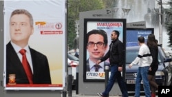 Young people pass beside boards with election posters of Gjorge Ivanov, left, current Macedonian President and a candidate of the ruling conservative VMRO-DPMNE party.