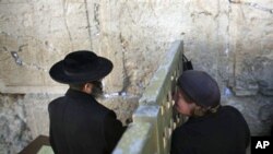 An ultra-Orthodox Jewish man and woman pray on either side of a fence at the Western Wall, the holiest site where Jews can pray, in Jerusalem's Old City, 15 Dec 2010