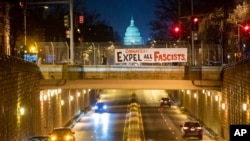 An activist with the group ShutDownDC takes a photo of a banner put up by the group calling on Congress to 'expel all fascists' on an overpass near the US Capitol in Washington on Jan. 5, 2022.