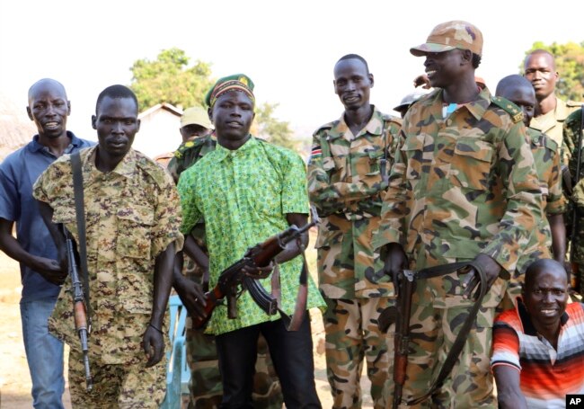 Government and opposition soldiers pose in the government barracks in Kajo Keji town, where 10 opposition soldiers were staying with the government troops in a makeshift soldier swap, in Kajo Keji county, South Sudan, Jan. 6, 2019.