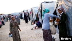 Kurdish refugees from the Syrian town of Kobani share bread in a camp in the southeastern town of Suruc, Sanliurfa province, Oct. 17, 2014. 